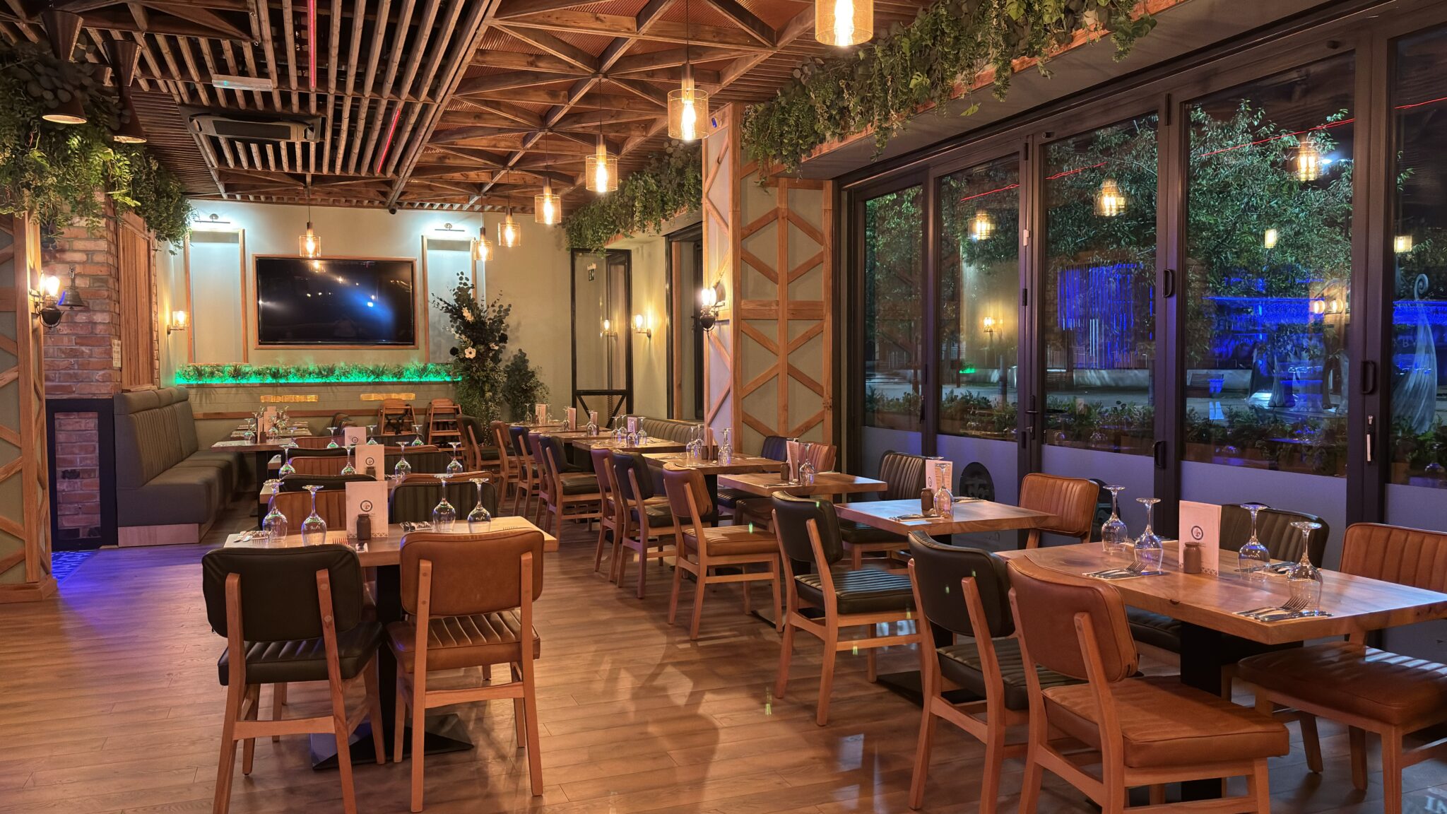The dining room at Casa Roni Kirkby, with booth seating, hanging greenery and folding windows